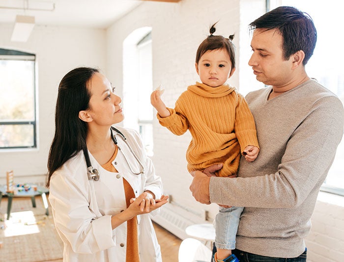 father with baby daughter at clinic with doctor