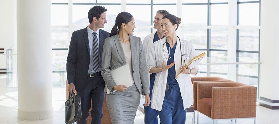 hosptial staff walking and talking with buisiness people