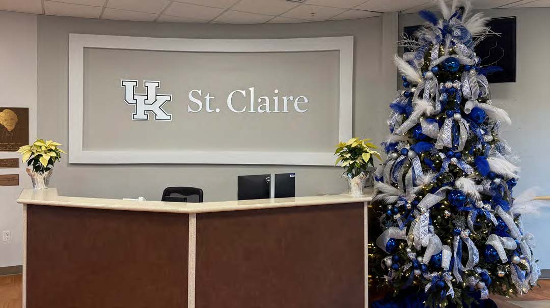 UK St. Claire Welcome Desk with poinsettias on the desk and a Christmas tree covered in doves to the right of the desk.