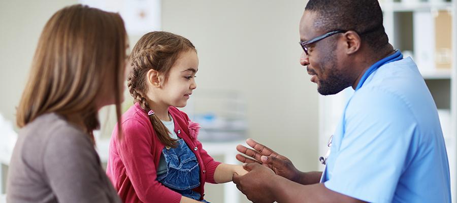 Image of young child and mother playing with physician