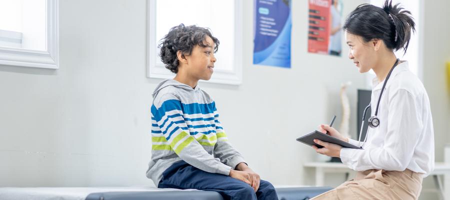 A boy sits with his doctor for an appointment.